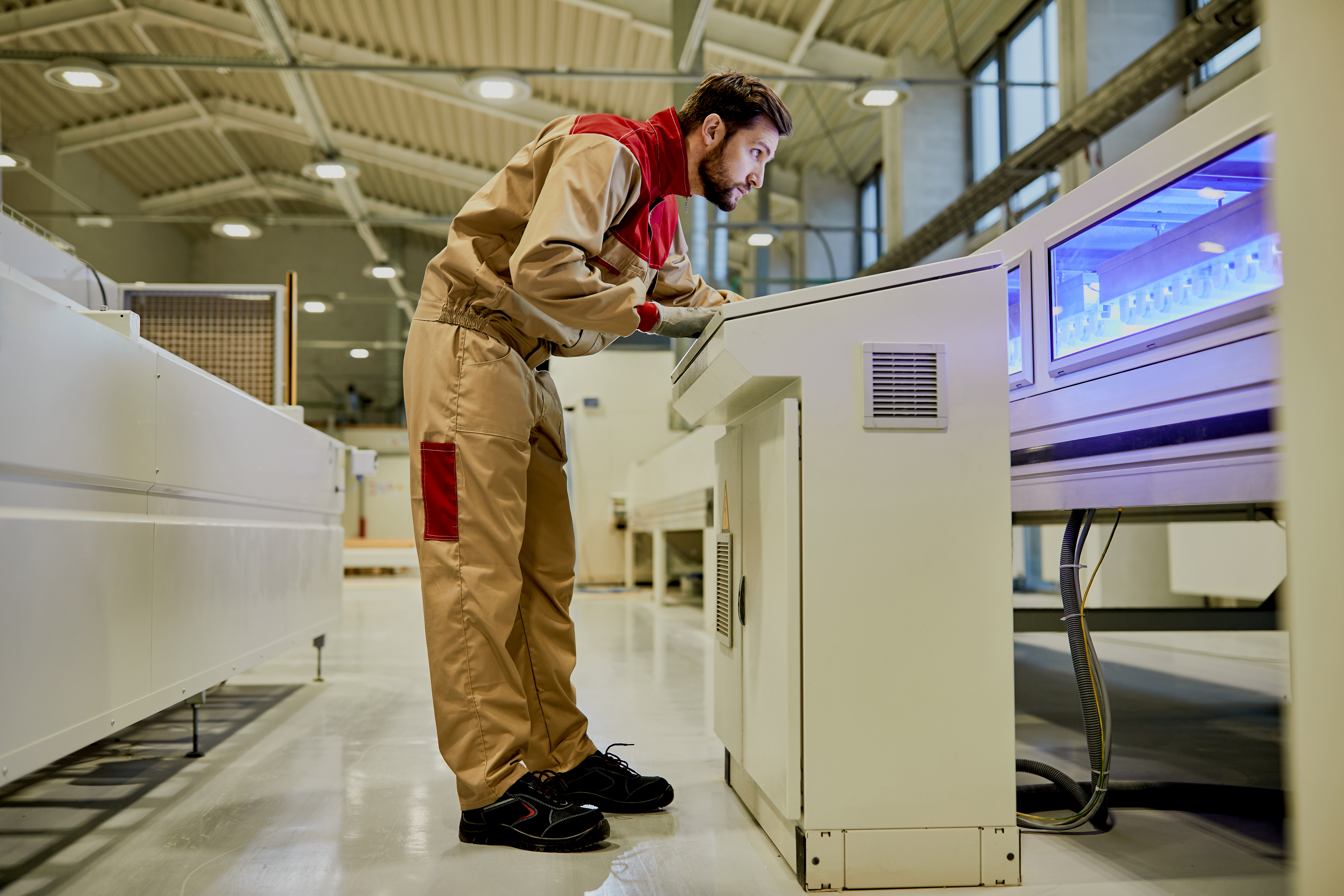 Production line worker operating automated machine at woodworkin